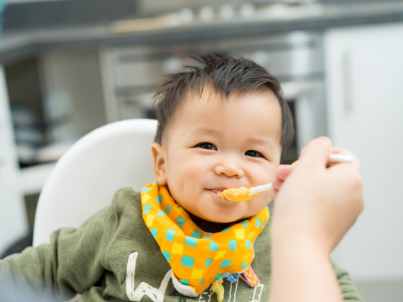 close up image of a toddler eating with bib on