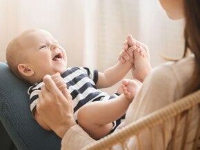 Baby on mothers lap holding mothers hand