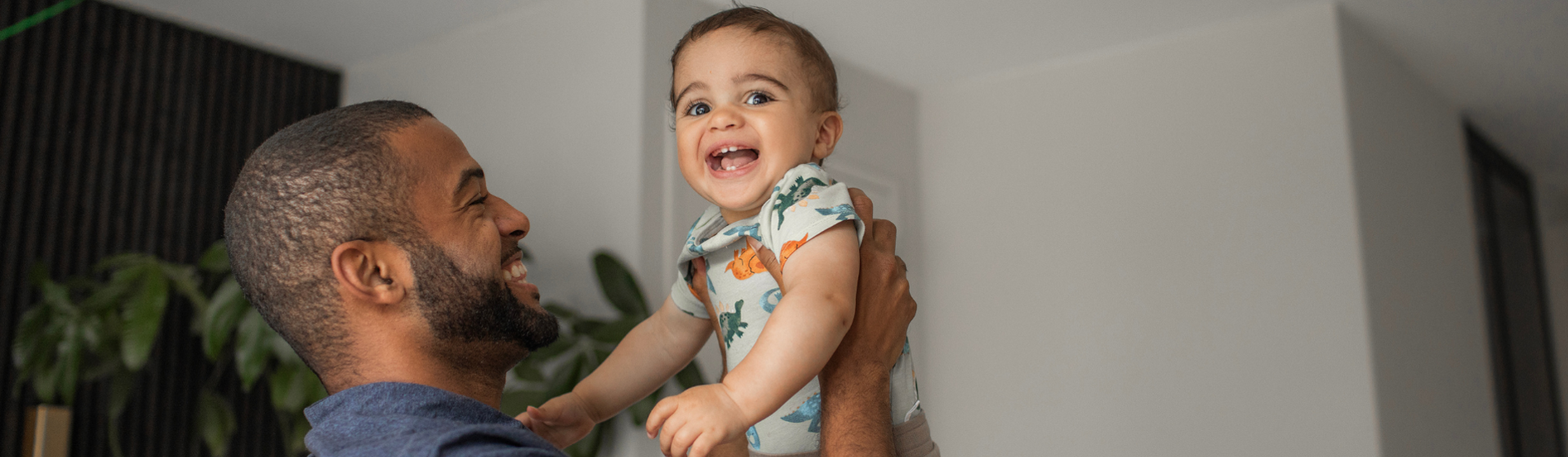 Father holding toddler in the air and laughing