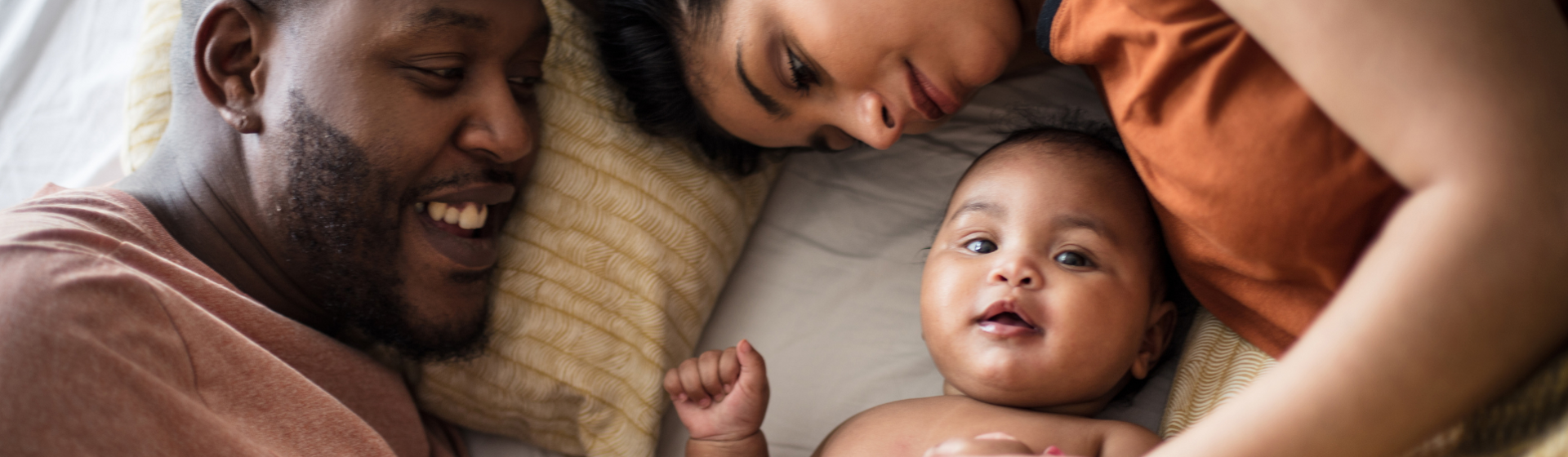 father and mother cuddling with their baby in bed